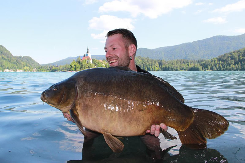 Porträtbild mit einem gefangenen Karpfen in einem See in den Bergen